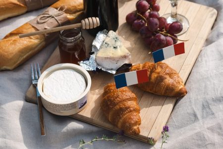 Authentic French picnic featuring croissants, cheese, and wine on a wooden board.